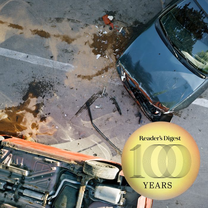 bird eye view of two car accident, one car is upside down; reader's digest 100 years logo in the corner of the frame