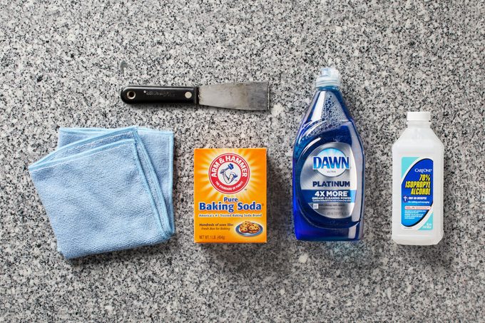 Granite countertop with cleaning cloth, baking soda, scraper, dish soap, and isoprophyl alcohol