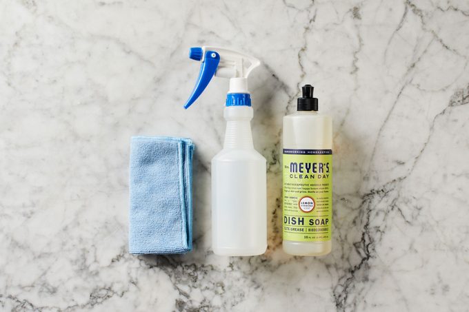 Mostrador de mármol con paño de limpieza, botella de spray y detergente