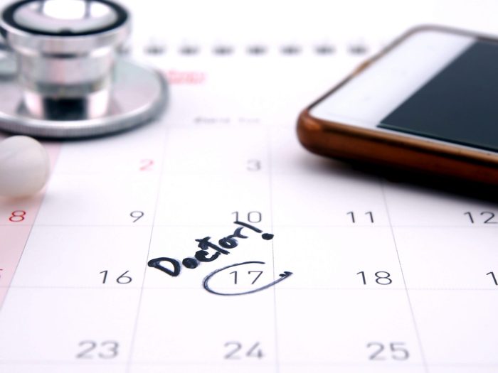 Doctor,appointment,reminder,on,calendar,with,mobile,phone;,medical,concept.