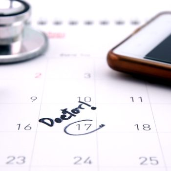 Doctor,appointment,reminder,on,calendar,with,mobile,phone;,medical,concept.