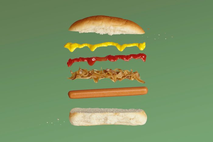 A deconstructed hot dog showing it's various layers against a green background