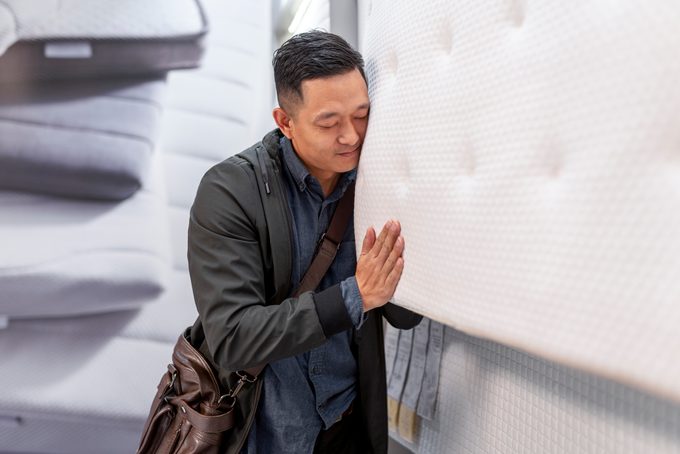 Asian man choosing for mattress while shopping