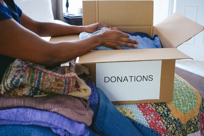 Una mujer prepara una caja de ropa para una donación