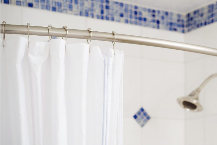 Detail shower curtain and shower head in blue and white tiled shower