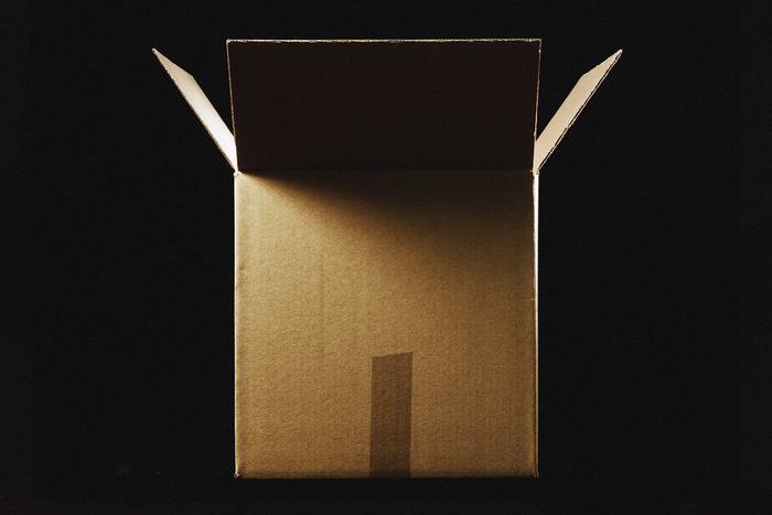 mysterious, unexpected cardboard box package on black background with dramatic lighting to represent brushing scam