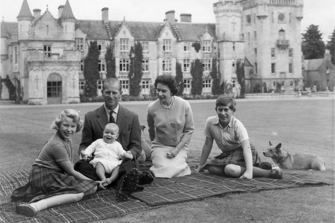 9th September 1960: Queen Elizabeth II and Prince Philip, Duke of Edinburgh with their children, Prince Andrew (centre), Princess Anne (left) and Charles, Prince of Wales sitting on a picnic rug outside Balmoral Castle in Scotland. Queen Victoria's husband, Prince Albert, purchased Balmoral Castle in 1846, and the small castle which stood in the 7,000 hectare wooded estate was redeveloped in the 1850s.The granite building was designed by Aberdeen architect William Smith with suggestions from Albert himself, who decided the interior decoration should represent a Highland shooting box with tartan or thistle chintzes, and walls decorated with trophies and weapons. Queen Victoria often visited the Highlands with her family, especially after Albertfs death in 1861, and Balmoral is still a popular retreat for the present royal family. (Photo by Keystone/Getty Images)