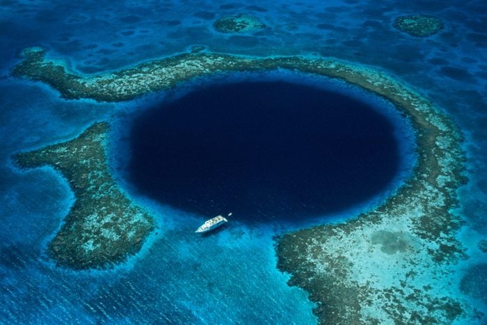 Belize, Lighthouse Reef, boat moored at Blue Hole, aerial view