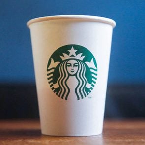 Is Starbucks Done with Disposable Paper Cups Paper Cup on Blue and Wood background