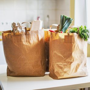 brown paper bags filled with groceries on a kitchen table