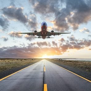Airplane landing on a road at sunset