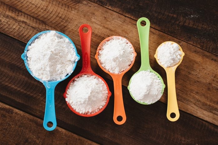 Colorful Measuring Cups filled with bread flour and all purpose flour On Wooden Table