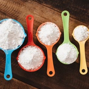 Colorful Measuring Cups filled with bread flour and all purpose flour On Wooden Table