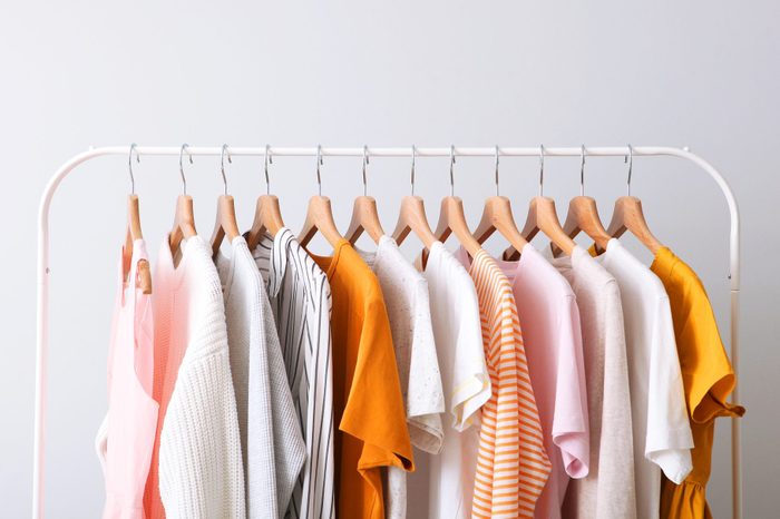 multiple outfits hang on a clothes rack against a gray background