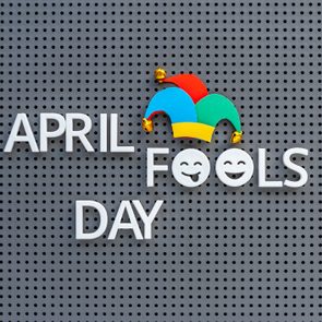 April Fools Day written on grey pegboard, jester hat decorates the lettering on gray background.