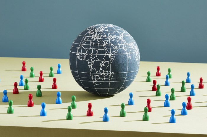 A world globe surrounded by people figurines