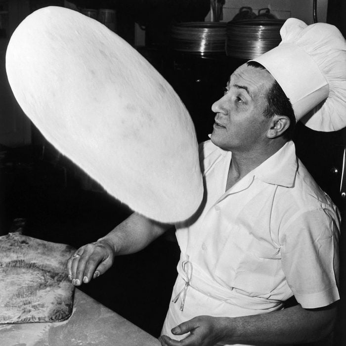 vintage photo of a man tossing pizza dough