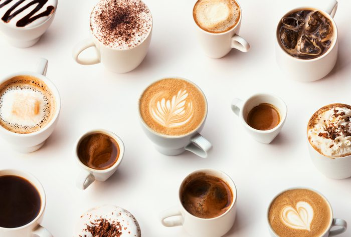 Many different types of coffee in white mugs on a white background