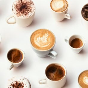 Many different types of coffee in white mugs on a white background