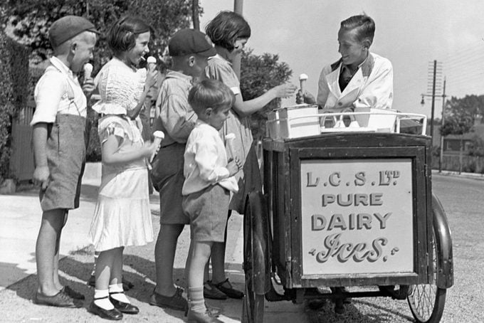 Niños comprando helado a un vendedor ambulante, c 1920.