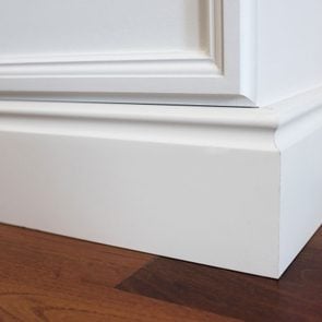 close up of white baseboard molding in a house with dark wood floor