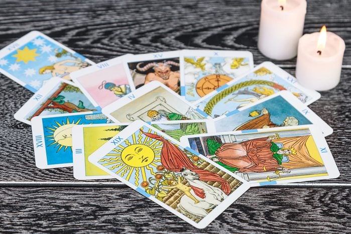 Close-Up Of Tarot Cards With Candles On Table