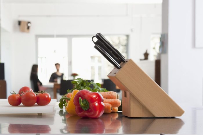 Tomatoes, carrots and bell peppers on a kitchen counter with knife block