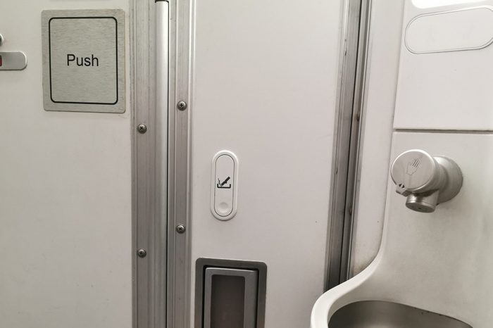 airplane bathroom with sink in the corner and ashtray on the wall