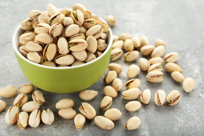 Tasty pistachios in bowl on gray background