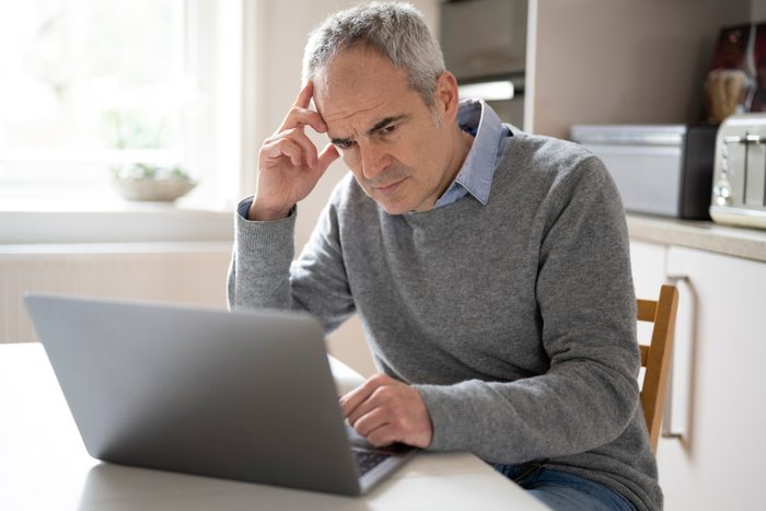 Caucasian man 53 years, using laptop device looking concerned