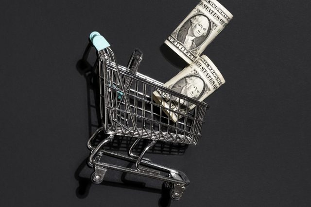 Shopping cart with dollar bills against black background