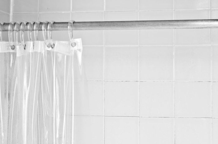Clear shower curtain liner with a white tile shower