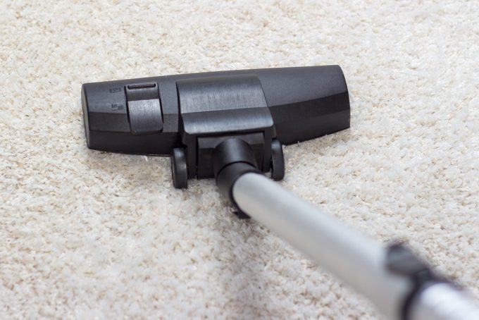 Vacuum cleaner being used to vacuum a carpet