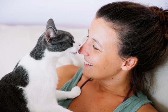 Cute femane cat licking her happy owner