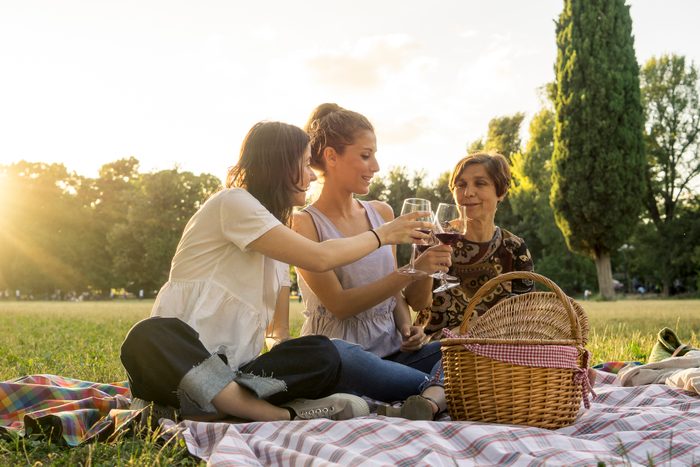 Mother and daughters drinking wine in a park during a picnic