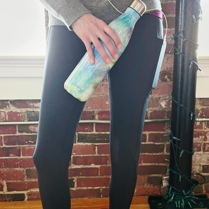 lower half of a woman in black leggings holding a water bottle