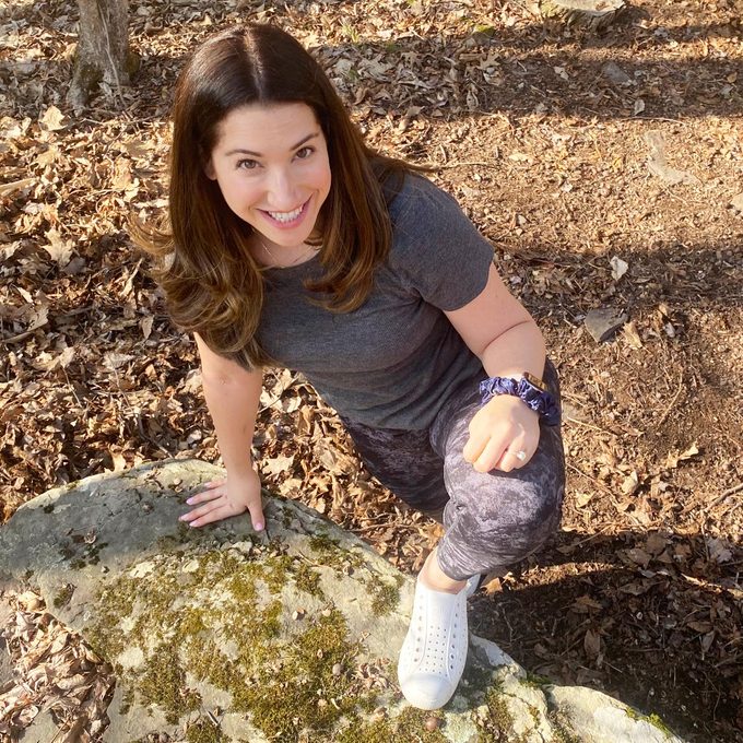 woman in leggings posing outside with one leg on a rock