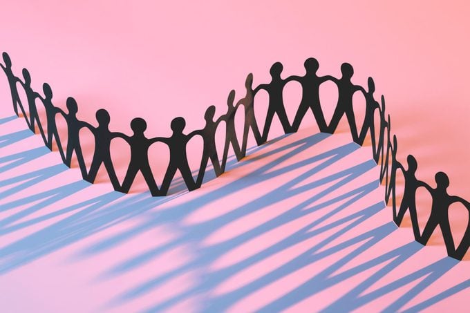 paper chain of people on a pink background with periwinkle cast shadows