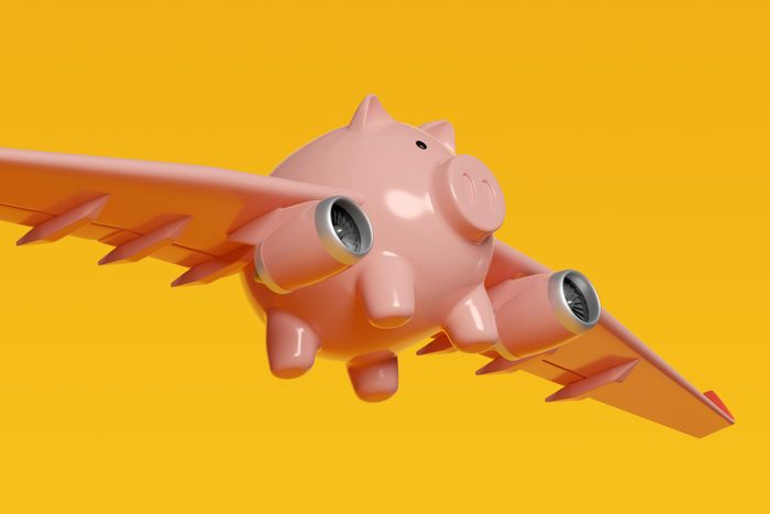 pink Piggy Bank with airplane wings on yellow background to illustrate budget airline concept