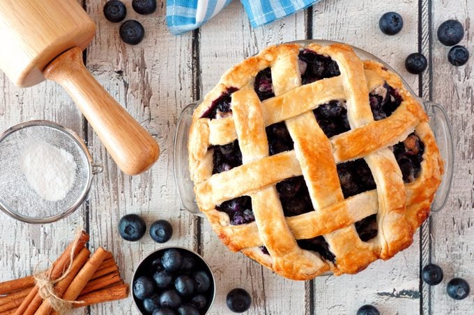 Homemade blueberry pie, top view baking scene over a white wood background