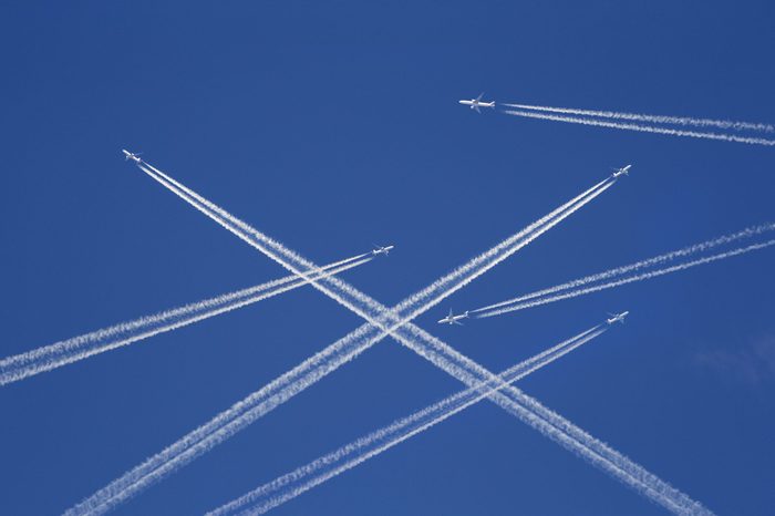 A lot of passenger airplanes on the air, busy air traffic, traveling high season starts concept. White planes against blue sky. Photo manipulation.