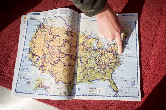 man pointing to map of the United States with marks for the national parks he has visited