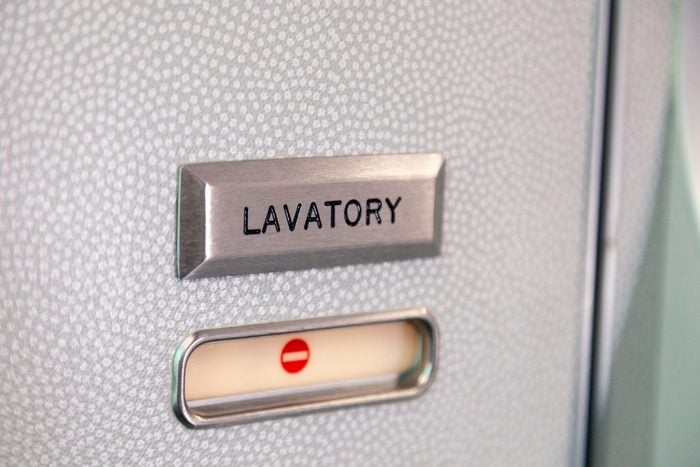 Vacant red sign, occupied symbol on an airplane lavatory door. Raised, brushed metal lavatory sign, recessed plastic vacant sign. Toilet room, wc, closet on airplane board