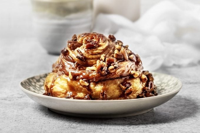 caramel Cinnamon roll with nuts on a plate on gray background