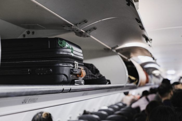 overhead locker on airplane with a black suitcase inside