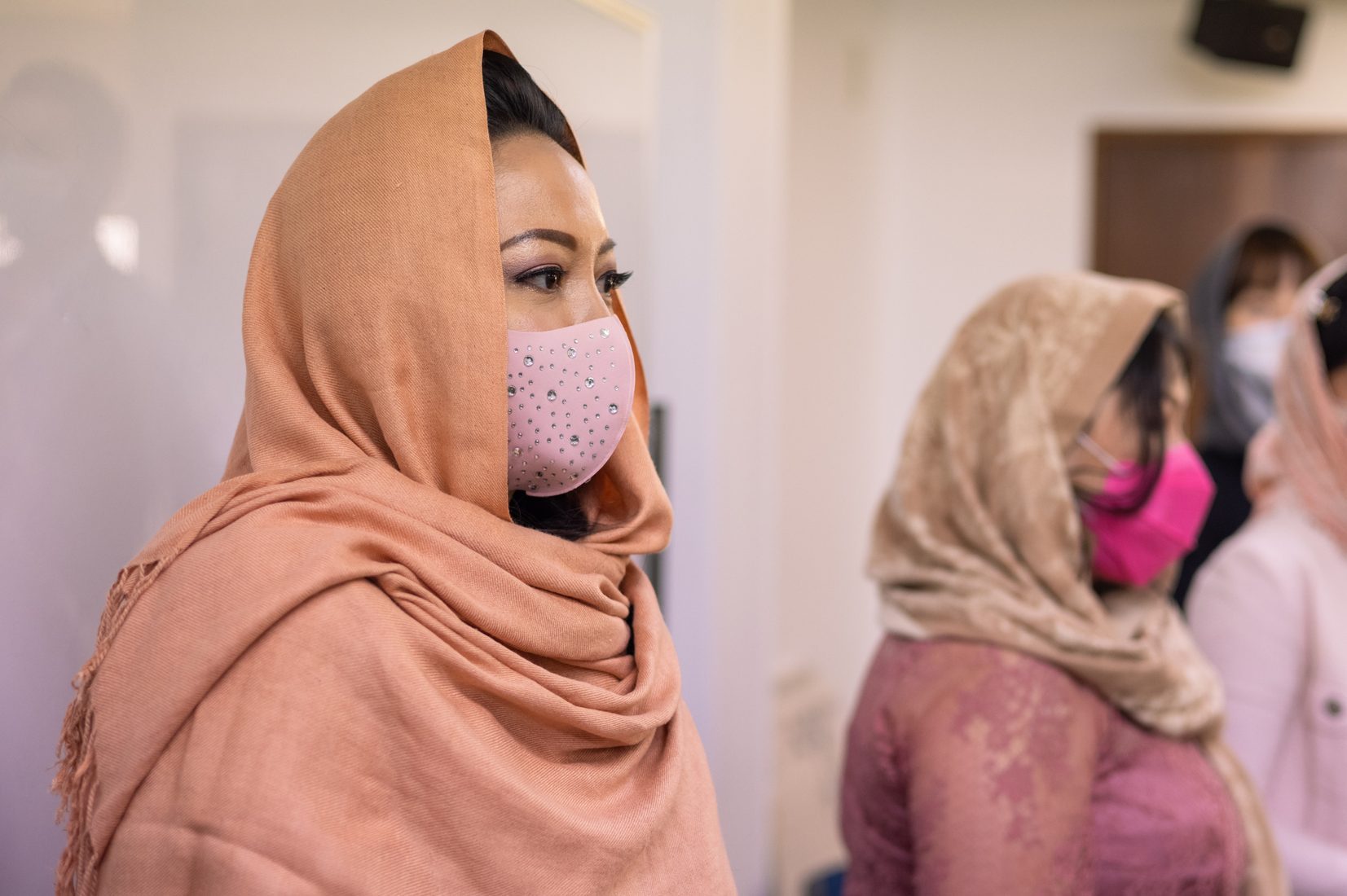 Asian bridesmaids in hijab and face mask moderating wedding ceremony using deigital tablet
