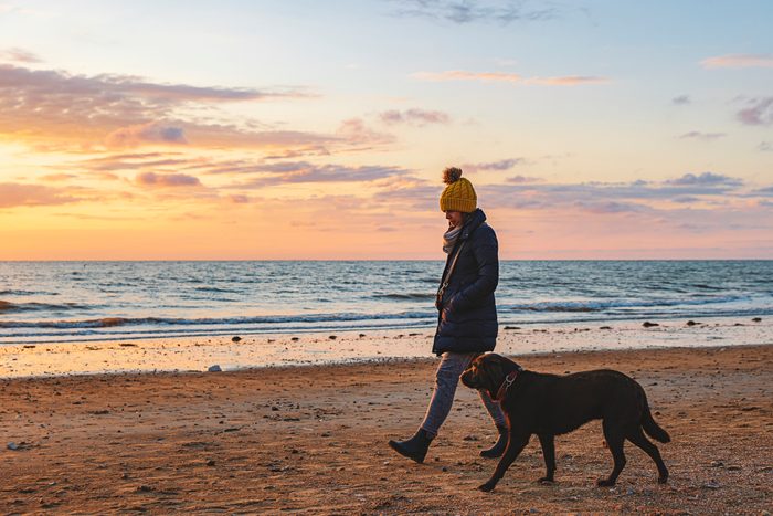 Woman walking her dog along the beach