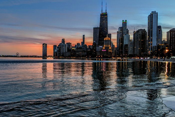 Illuminated Buildings By Lake Against Sky During Sunset in Chicago