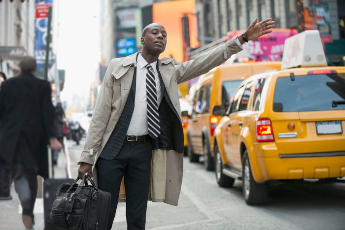Black businessman hailing taxi on city street