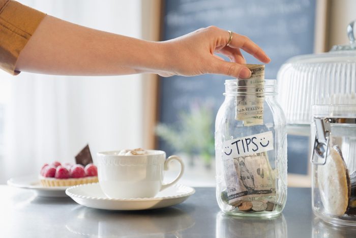 Caucasian hand putting money in tip jar